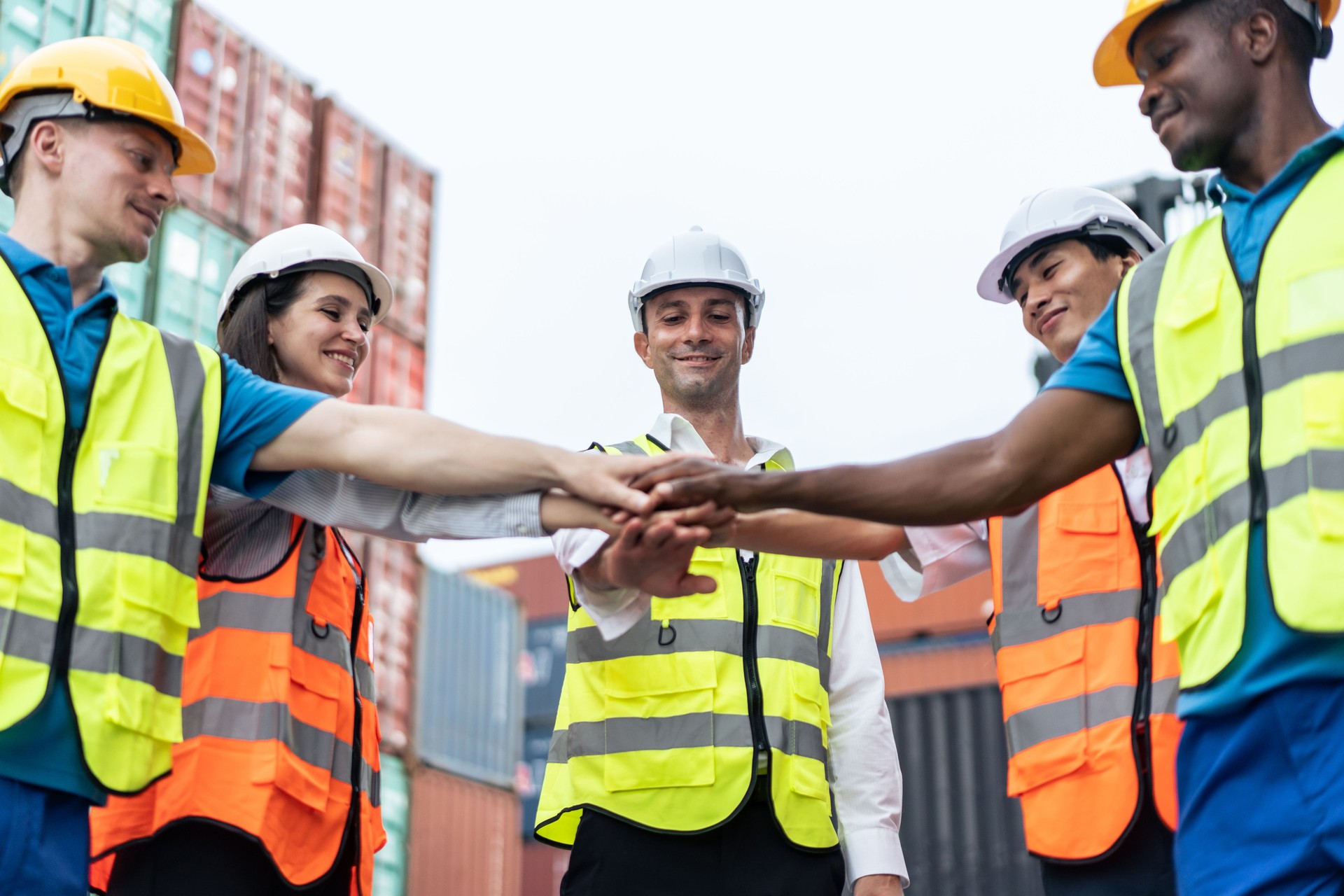Group of man and woman worker put hand on each other in container port. Attractive young business woman and foreman feel happy after processes order success at warehouse logistic in cargo freight ship